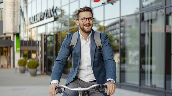 Fahrradfahrer dynamisch vor moderner Glasfassade
